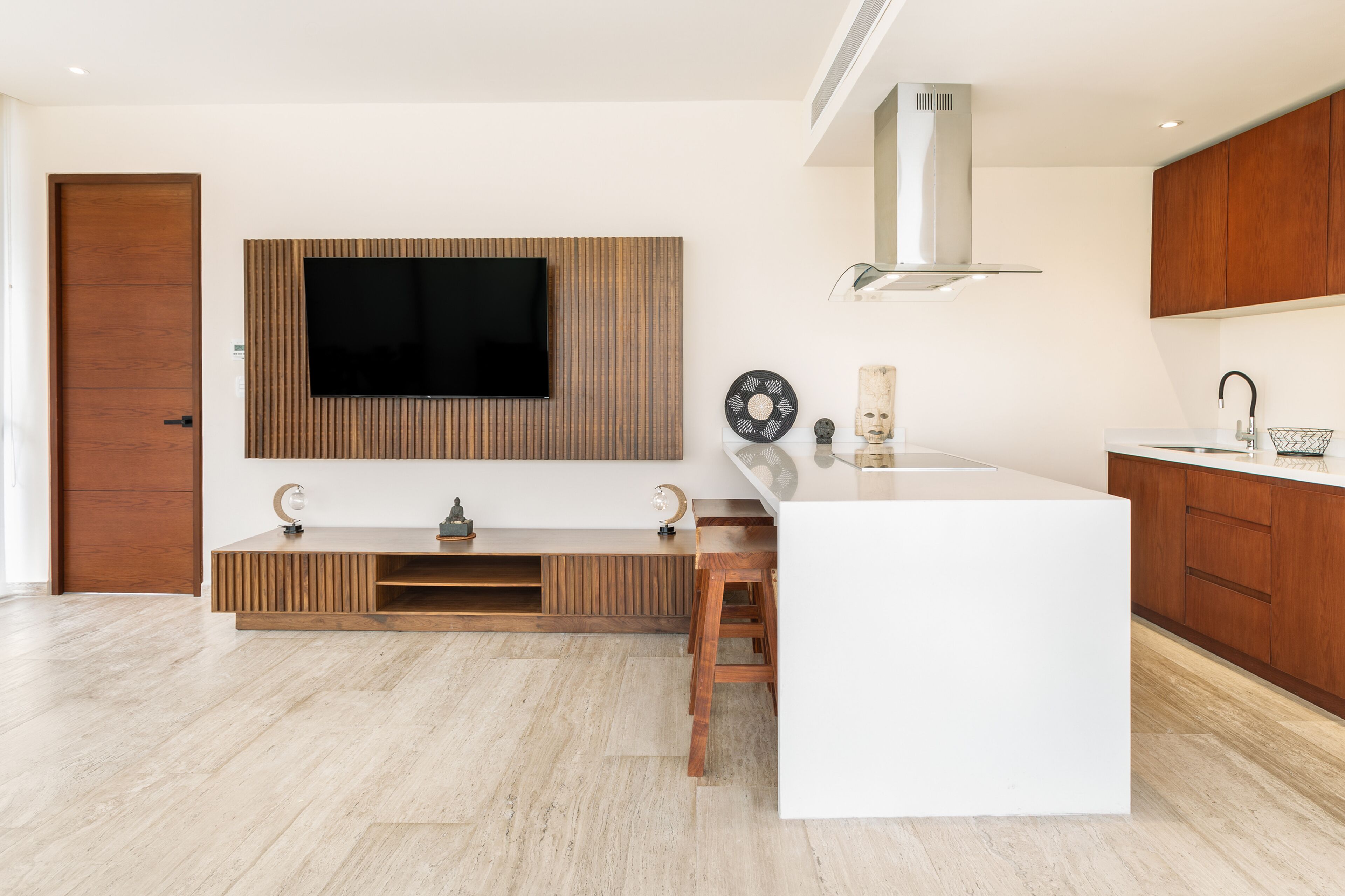 Een moderne keuken met een ingebouwde televisie, houten kastjes en een wit aanrecht.