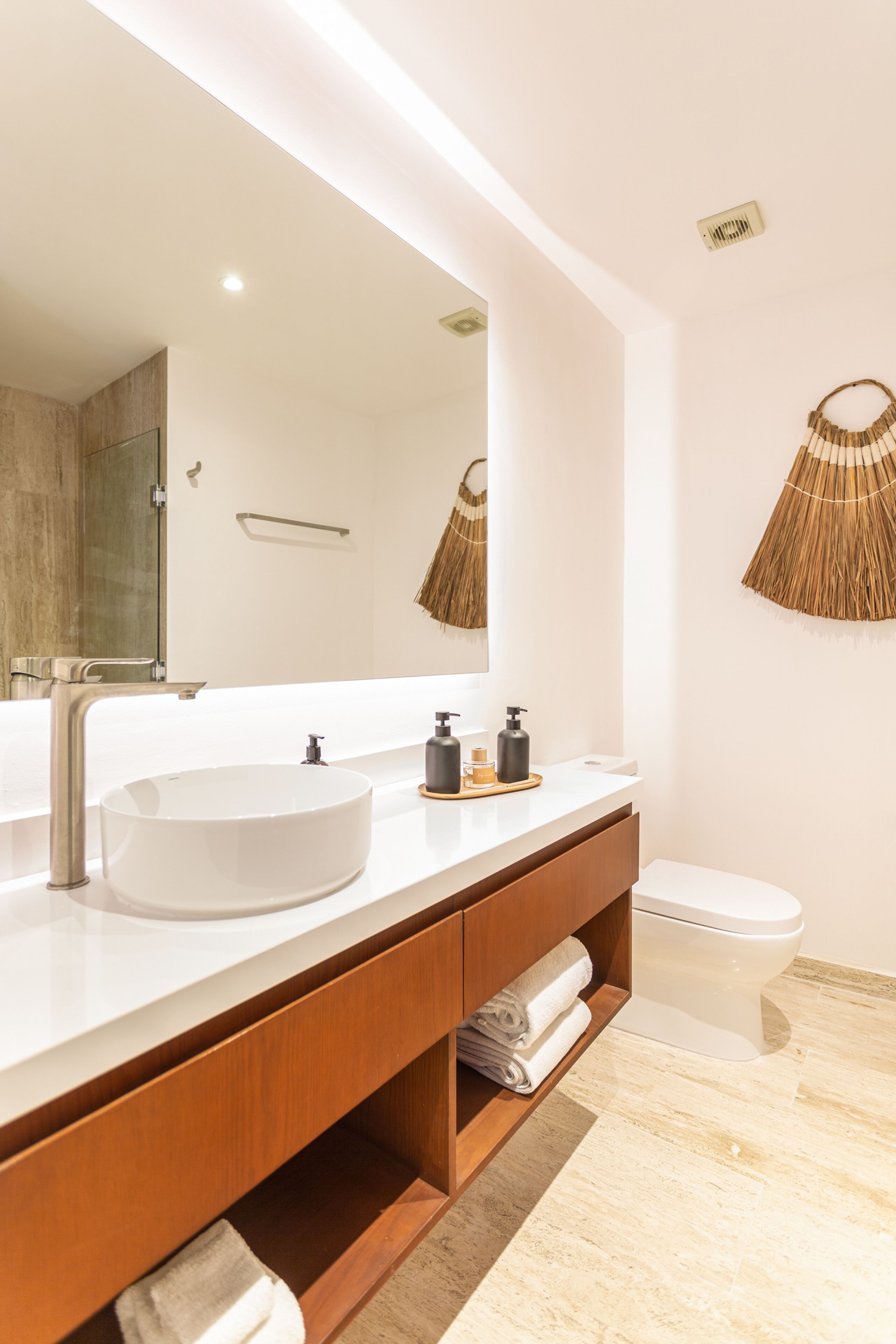 Een moderne badkamer met een grote spiegel, een rond wastafel en een toilet.