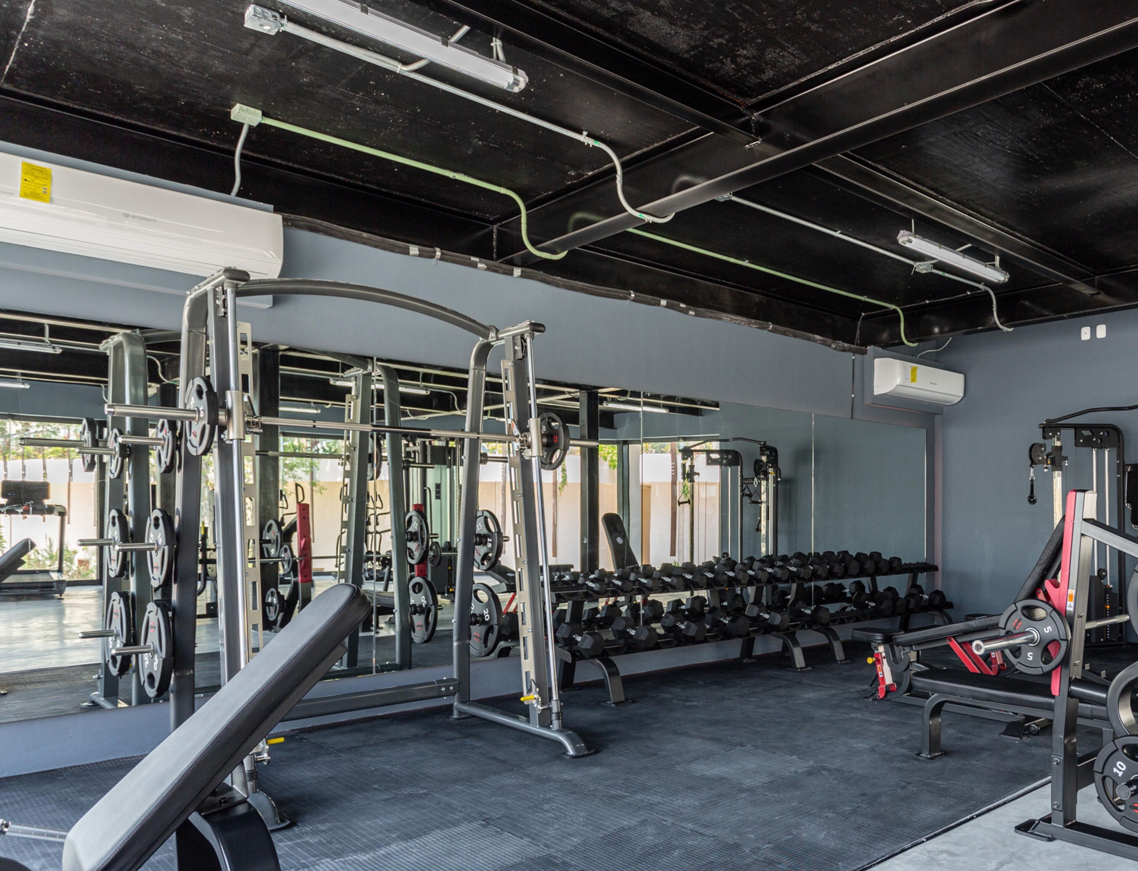 A gym with weightlifting equipment, benches, and dumbbells.