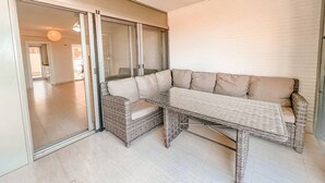 Una sala de estar moderna con un sofá modular, un vidrio corredizo que da a otra habitación y un ventilador de techo.