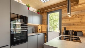 A modern kitchen with grey cabinets, a built-in oven, and a large window. - Chalet  with 4 bedrooms & wellness (Biberwier)