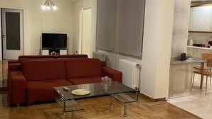 Amplia sala de estar con un sofá rojo, una mesa de centro de vidrio y una televisión.