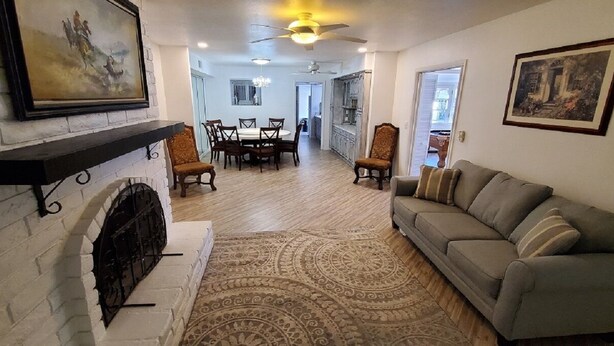 A living room with a fireplace, a sofa, a dining area with chairs, and a ceiling fan. - Huge 4,080 SqFt  cul-de-sac Home (Mesa)