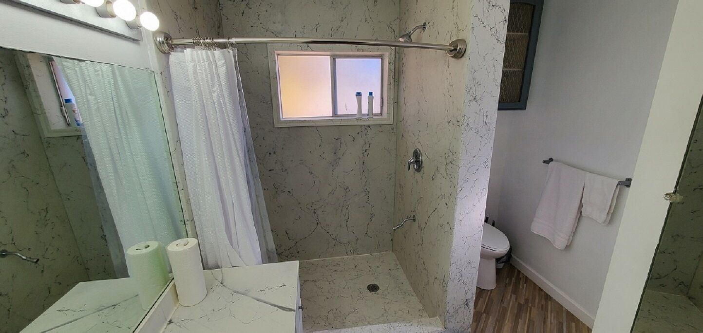 A bathroom with a shower, toilet, and a window with a view.