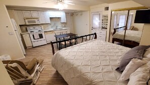 A compact bedroom with a bed, bedside table, and a mirror. Adjacent is a kitchenette with a microwave, oven, and sink. - Huge 4,080 SqFt  cul-de-sac Home (Mesa)