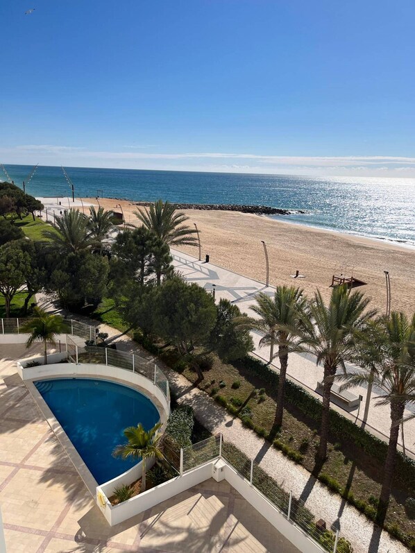 A pool area with a view of the beach and ocean.