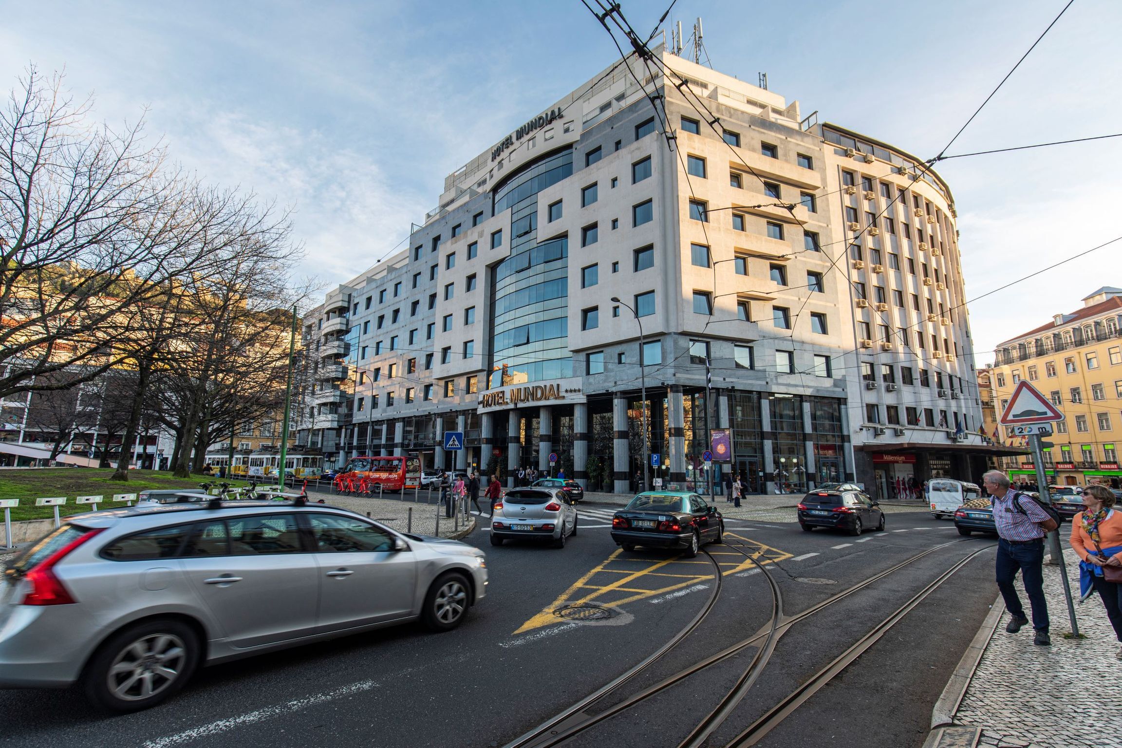 A modern hotel with a curved facade, multiple floors, and a prominent entrance.