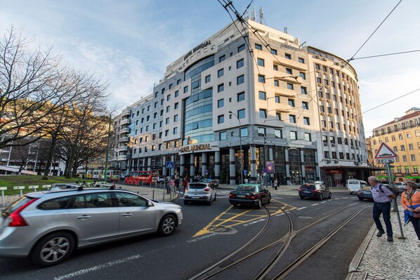 A modern hotel with a curved facade, multiple floors, and a prominent entrance.