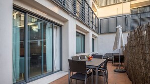 An outdoor patio with a table and chairs, a basket of fruit, and a woven fence. - Downtown apartment w/terrace (Lisboa)