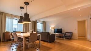 A modern living room with a dining area, a sofa, a TV, and a lamp. - Downtown apartment w/terrace (Lisboa)