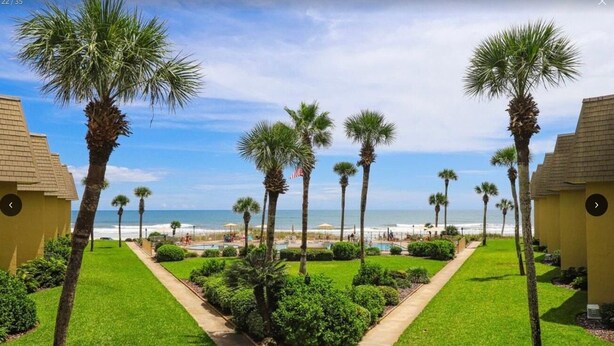 A resort with a central pathway flanked by palm trees and a view of the beach. - Ocean view from every angle, Walkout property steps to the beach, Sunsets Galore (St. Augustine)