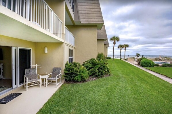 A building with a balcony, outdoor seating, and a well-maintained lawn. - Ocean view from every angle, Walkout property steps to the beach, Sunsets Galore (St. Augustine)