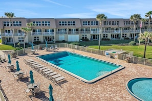 A hotel with a pool area, including lounge chairs and umbrellas, and a building with multiple balconies. - Ocean view from every angle, Walkout property steps to the beach, Sunsets Galore (St. Augustine)