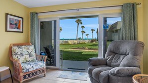 A room with a view of the beach, a wicker chair, a grey sofa, and a small table. - Ocean view from every angle, Walkout property steps to the beach, Sunsets Galore (St. Augustine)