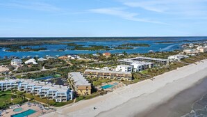 An aerial view of a coastal resort with multiple buildings, a beach, and a marina. - Ocean view from every angle, Walkout property steps to the beach, Sunsets Galore (St. Augustine)