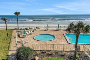 A pool area with a view of the beach and ocean.