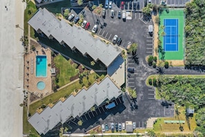 An aerial view of a hotel with multiple parking lots, a tennis court, and a pool area. - Ocean view from every angle, Walkout property steps to the beach, Sunsets Galore (St. Augustine)