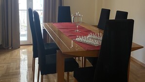 A dining area with a wooden table, black chairs, a red table runner, and a chessboard. - An elegant apartment in one of the most central areas of Athens. (Αθήνα)