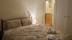 A neatly made bed with a floral-patterned bedspread, a bedside lamp, and a star-shaped hanging light fixture. - An elegant apartment in one of the most central areas of Athens. (Αθήνα)