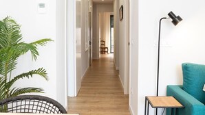 A hallway with wooden flooring, white walls, and a teal sofa. - Bravissimo Pont Areny, modern 3-bedroom apartment next to the historic center (Girona)
