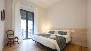 A bedroom with a wooden bed, a chair, a window with curtains, and a balcony. - Bravissimo Pont Areny, modern 3-bedroom apartment next to the historic center (Girona)