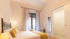 Une chambre à coucher avec un lit, une chaise, une lampe, une fenêtre et une porte.