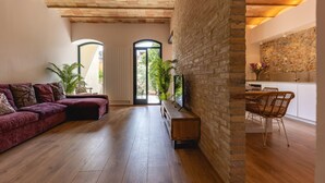 A cozy living room with a wooden floor, a red sofa, and a stone wall. - Bravissimo Plaça de la Independència, Garden View; High-quality luxury apartment (Girona)