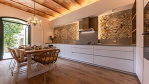 A modern kitchen with a stone backsplash, wooden flooring, and a dining area with a chandelier. - Bravissimo Plaça de la Independència, Garden View; High-quality luxury apartment (Girona)