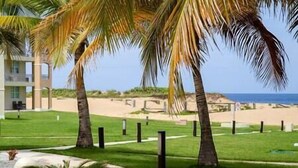 Un resort con palme, una spiaggia e un edificio con balconi.
