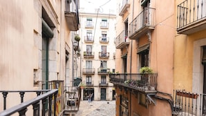 A narrow cobblestone street flanked by buildings with balconies, some with plants. - Bravissimo Ferreries, unique 3-bedroom apartment (Girona)