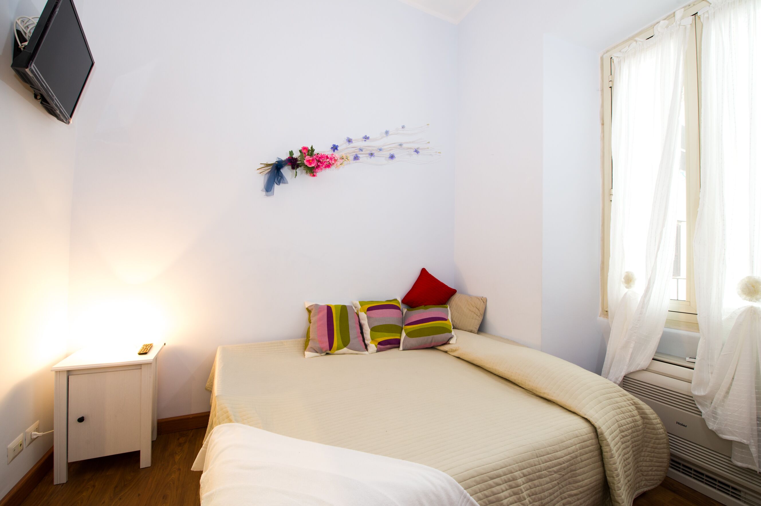 Une chambre à coucher avec un lit, une table de chevet et un téléviseur fixé au mur.