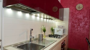 Uma cozinha com pia de aço inoxidável, fogão a gás e micro-ondas.