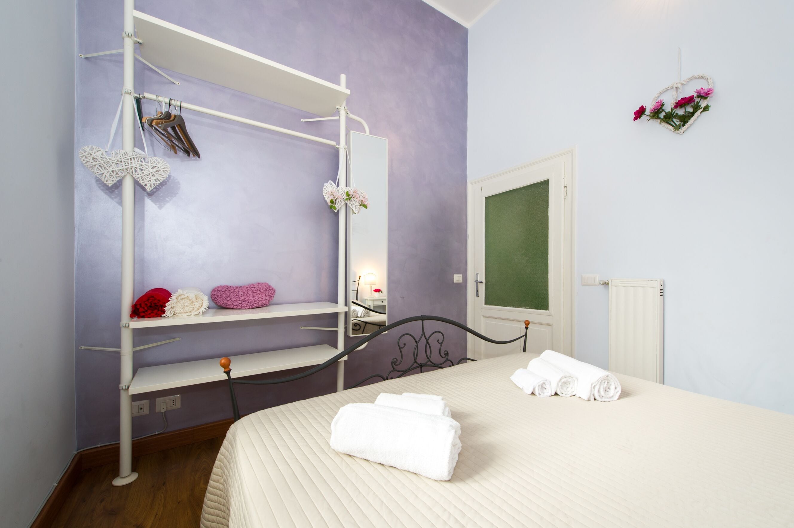 A bedroom with a bed, a wardrobe, a mirror, and a radiator.