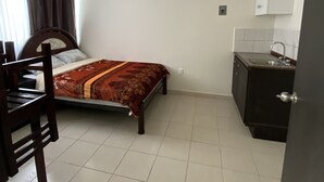 A bedroom with a bed, a desk, and a kitchenette. - room rental (Tehuacán)