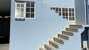 A two-story building with a light blue exterior, a set of beige stairs, and multiple windows. - room rental (Tehuacán)