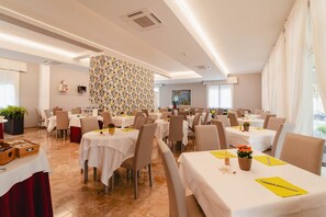 Un vaste espace dédié à la salle à manger, comprenant plusieurs tables, des chaises et un mur décoratif.