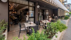 Ein Straîfencafé mit Tischen, Stühlen und einer Speisekarte, mit Blick auf die Straße.