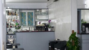 Eine moderne Bar mit einer Theke, Regalen voller Spirituosen und einer Sitzgelegenheit mit Tischen und Stühlen.