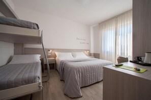 Une chambre d’hôtel avec des lits superposés, un bureau avec une machine à café et un mur orné d’une citation inspirante.