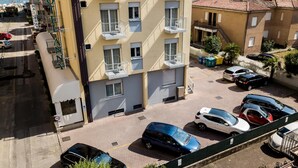 Ein Hotel mit mehreren Balkonen, einem Parkplatz und Meerblick.
