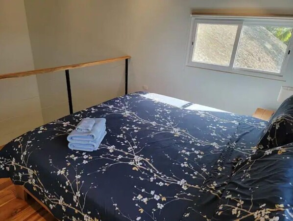 Une chambre à coucher avec un lit, une fenêtre et un plancher en bois.