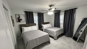 Ein Schlafzimmer mit zwei Betten, einem Deckenventilator und einem großen Spiegel.