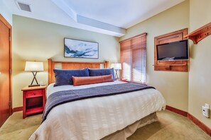 Una camera d'albergo con un letto grande, due comodini con lampade, una TV a parete e una luce a soffitto.