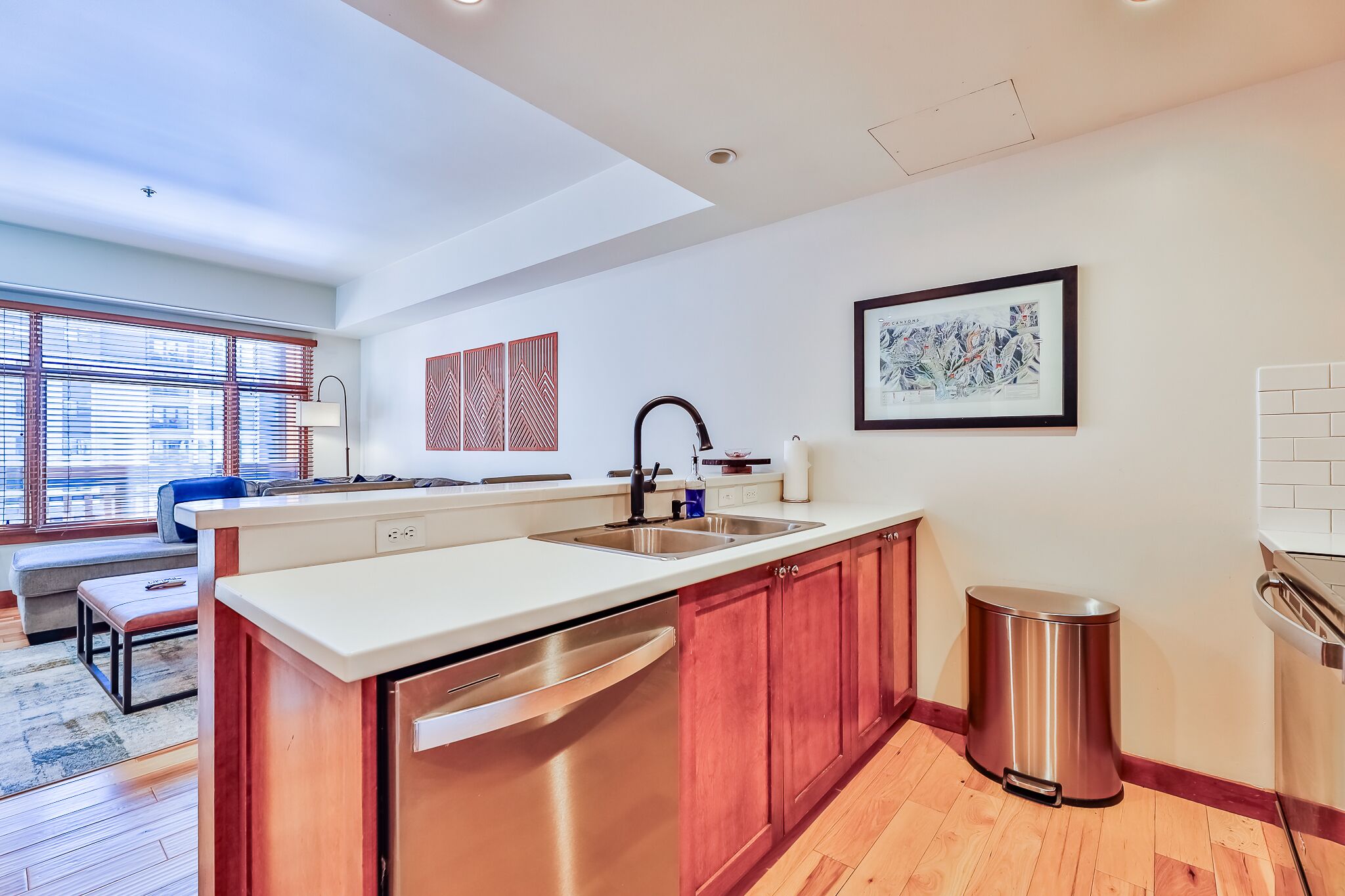 A modern kitchen with a dishwasher, sink, and stainless steel trash can.