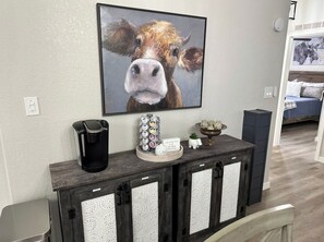 Cozy living room with a large painting and a console table featuring a coffee maker.