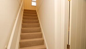 A carpeted staircase with white walls and a small window at the top. - Firkin Cottage (Bedale)