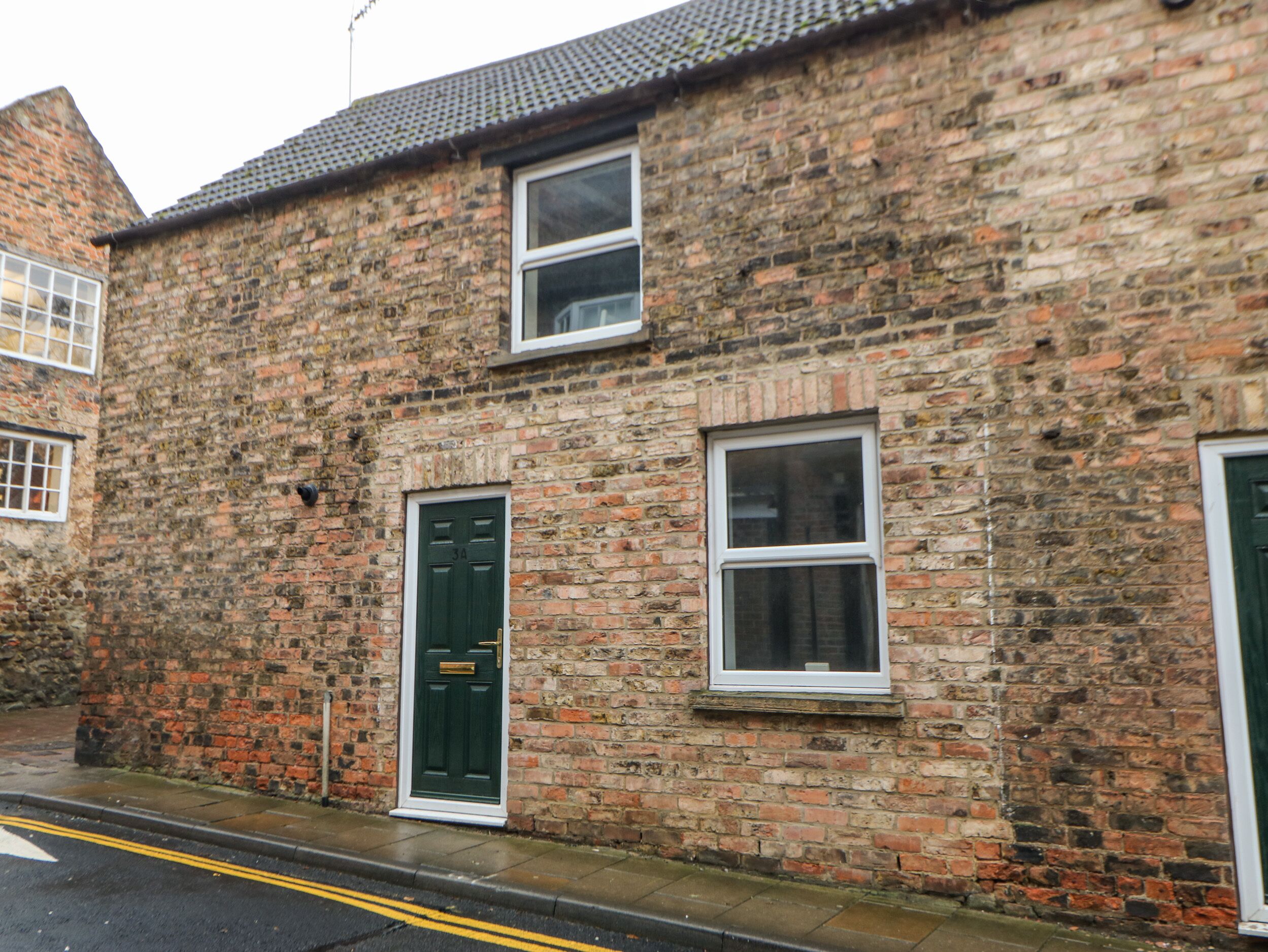 A brick building with two windows and a green door.