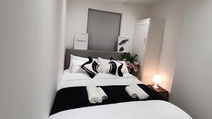 A modern hotel room with a neatly made bed, a bedside lamp, and a large mirror on the wall. - “Family-Friendly Fun: Spacious Home Near Top Attractions” (Ironville)