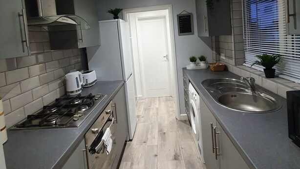 A modern kitchen with grey cabinets, a stainless steel range hood, a built-in oven, a double sink, and a window with blinds. - “Family-Friendly Fun: Spacious Home Near Top Attractions” (Ironville)
