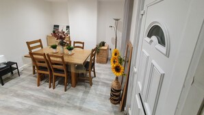 A dining area with a wooden table and chairs, a vase with flowers, and a tall floor lamp. - “Family-Friendly Fun: Spacious Home Near Top Attractions” (Ironville)